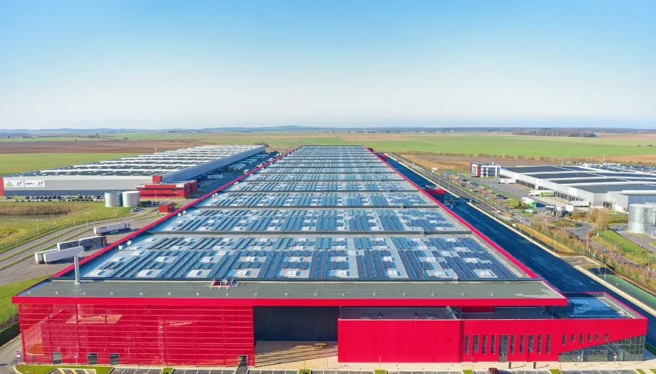 Vue aérienne d'un entrepôt logistique rouge et gris équipé de panneaux solaires