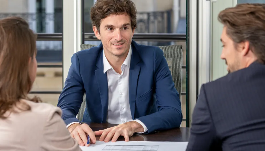 Un conseiller échangeant avec deux clients autour d'un document, pour préparer sa retraite
