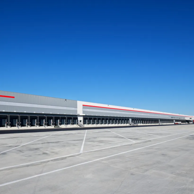 Longue façade blanche et grise avec liseré rouge et quais de chargement d'un entrepôt logistique
