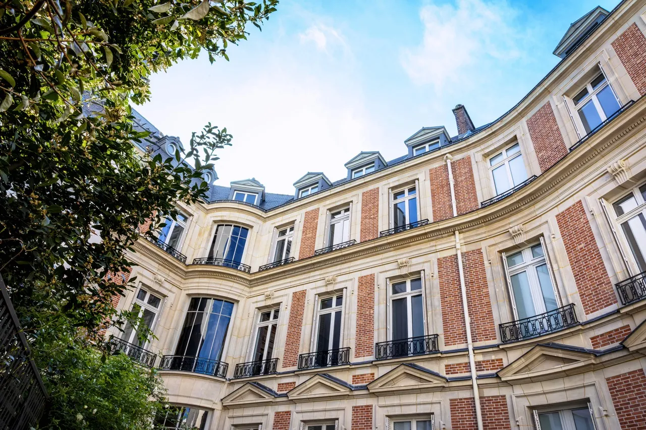 Vue en contre-plongée de la cour intérieure d'un immeuble en pierre et brique, de style classique parisien